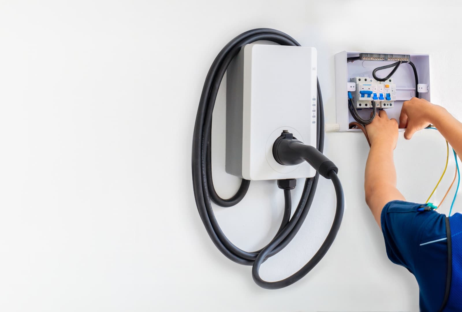 A wall-mounted Level 2 electric vehicle charger being wired during installation.
